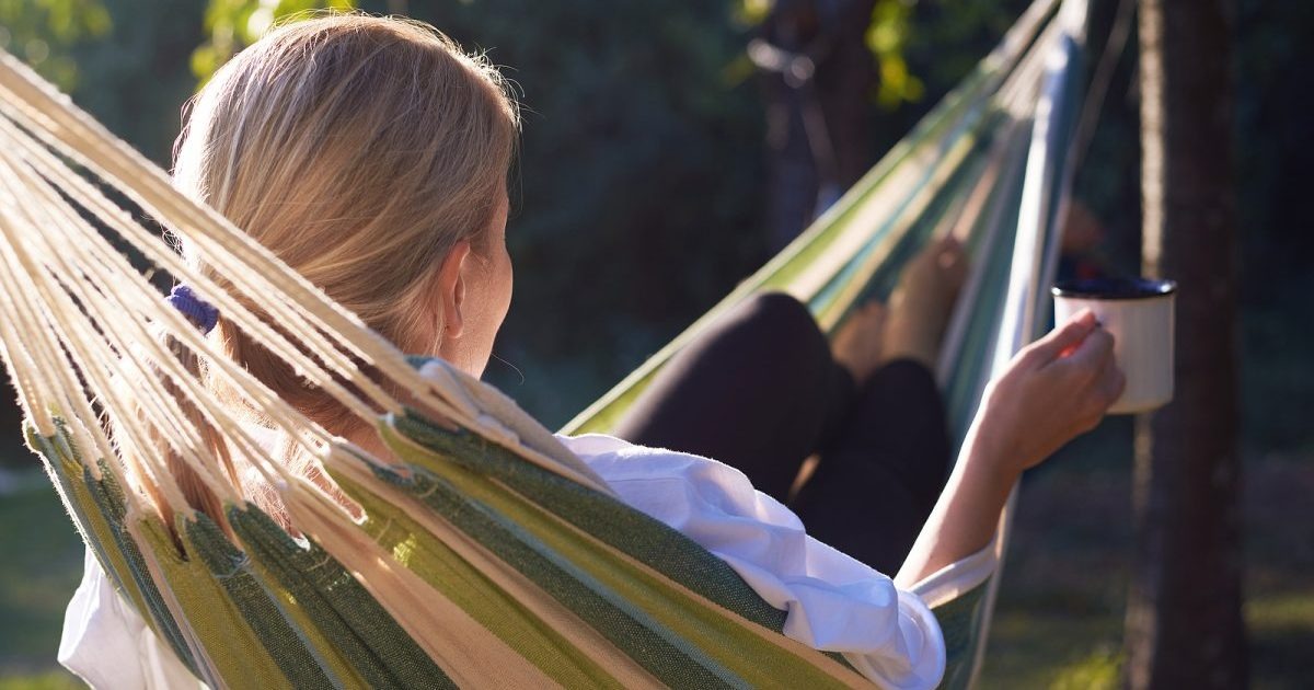 woman relaxing with coffee in hammock